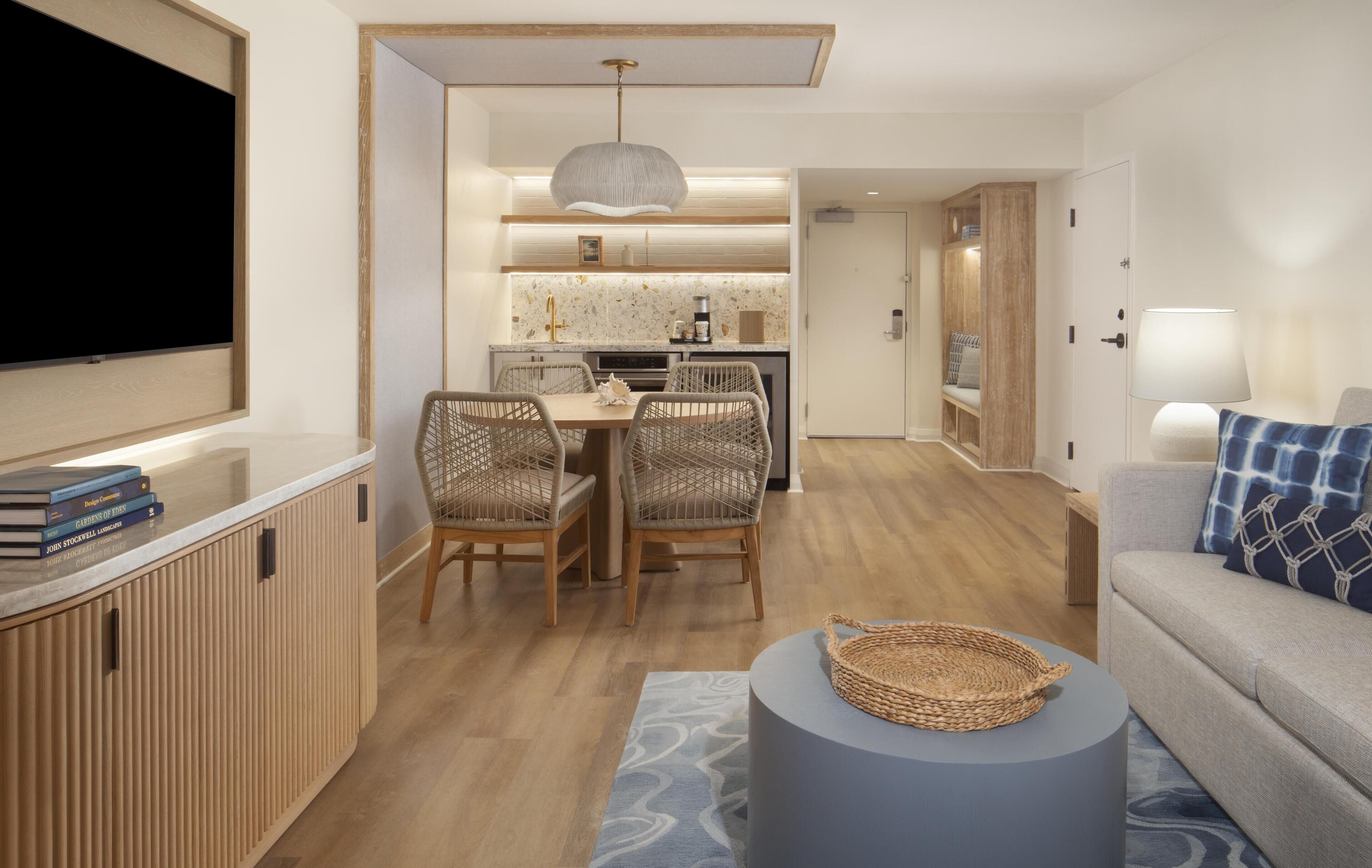 A modern living room with a TV, sofa, and dining area with chairs.