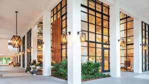 A modern hotel lobby with large windows, geometric light fixtures, and indoor plants. - Baker's Cay Resort Key Largo, Curio Collection by Hilton (Key Largo)