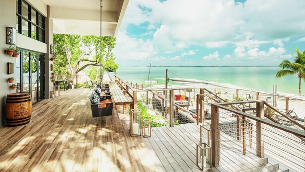 A wooden deck with a view of the ocean and a palm tree. - Baker's Cay Resort Key Largo, Curio Collection by Hilton (Key Largo)
