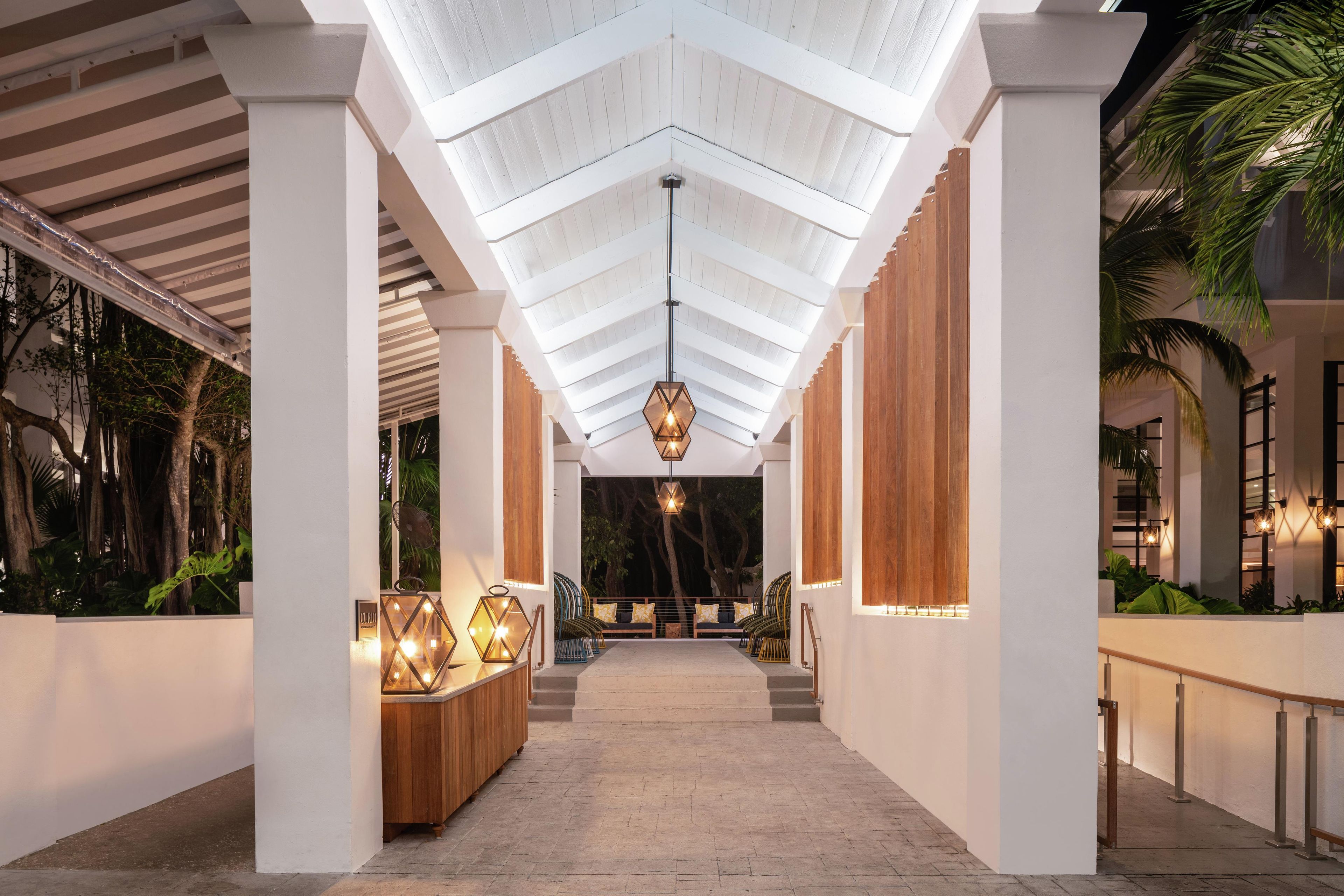 Een gang met hoog plafond, houten kolommen en een centraal hanglamp.