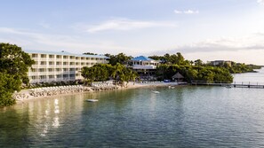 A beachfront hotel with multiple balconies, a pool, and a beach area with lounge chairs.