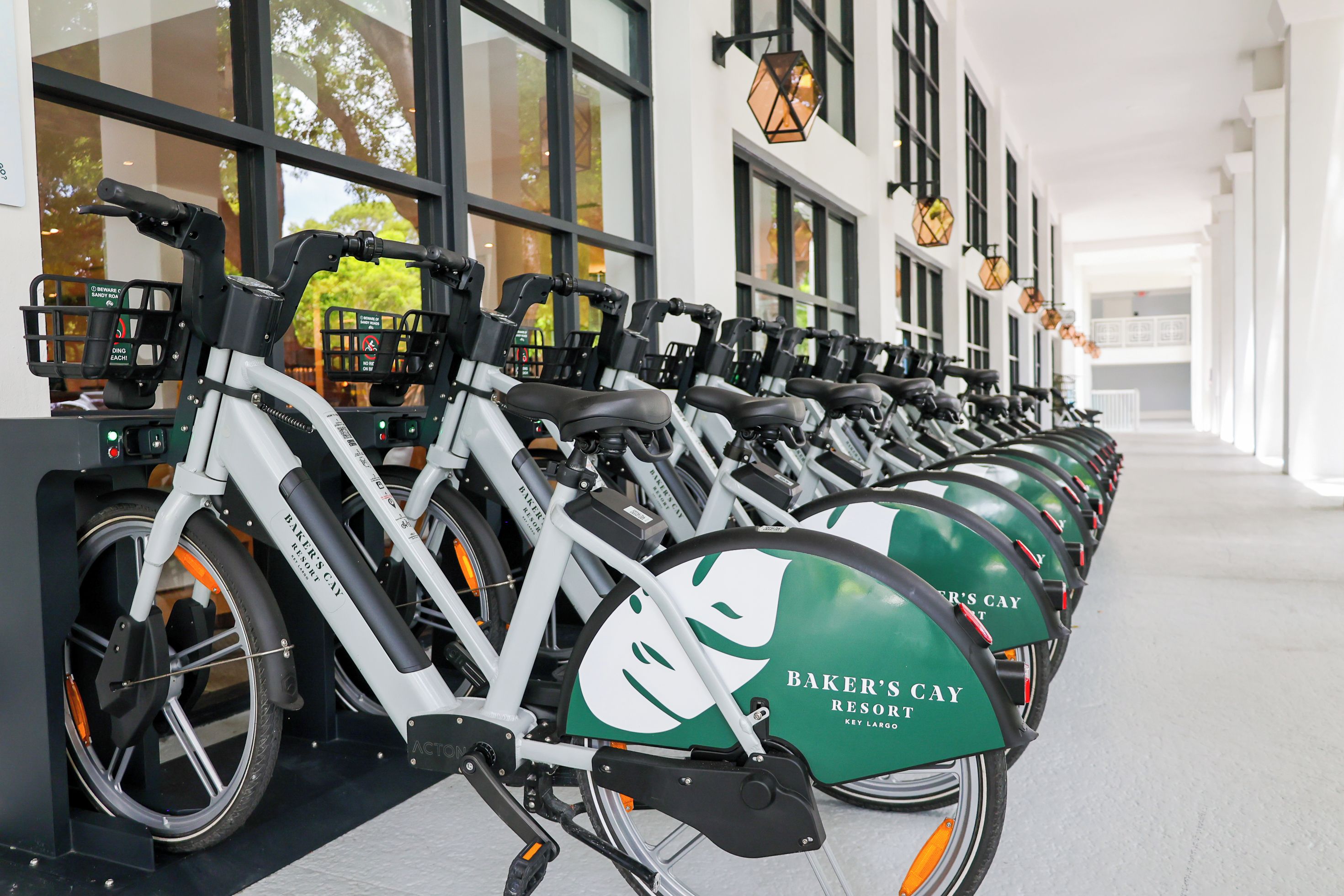 Fileira de bicicletas ergométricas com marcação verde na entrada de um hotel.
