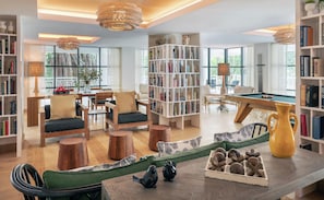 A spacious living room with a pool table, bookshelves, and comfortable seating.