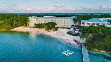 Un resort con playa, un muelle con barcos y un edificio grande con varios balcones.