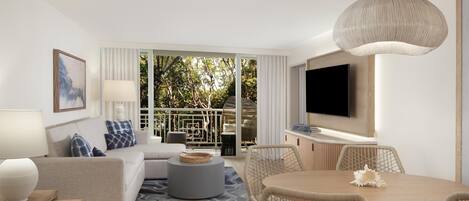 A modern living room with a sofa, coffee table, dining table, wicker chairs, a TV, and a balcony with a view of trees.