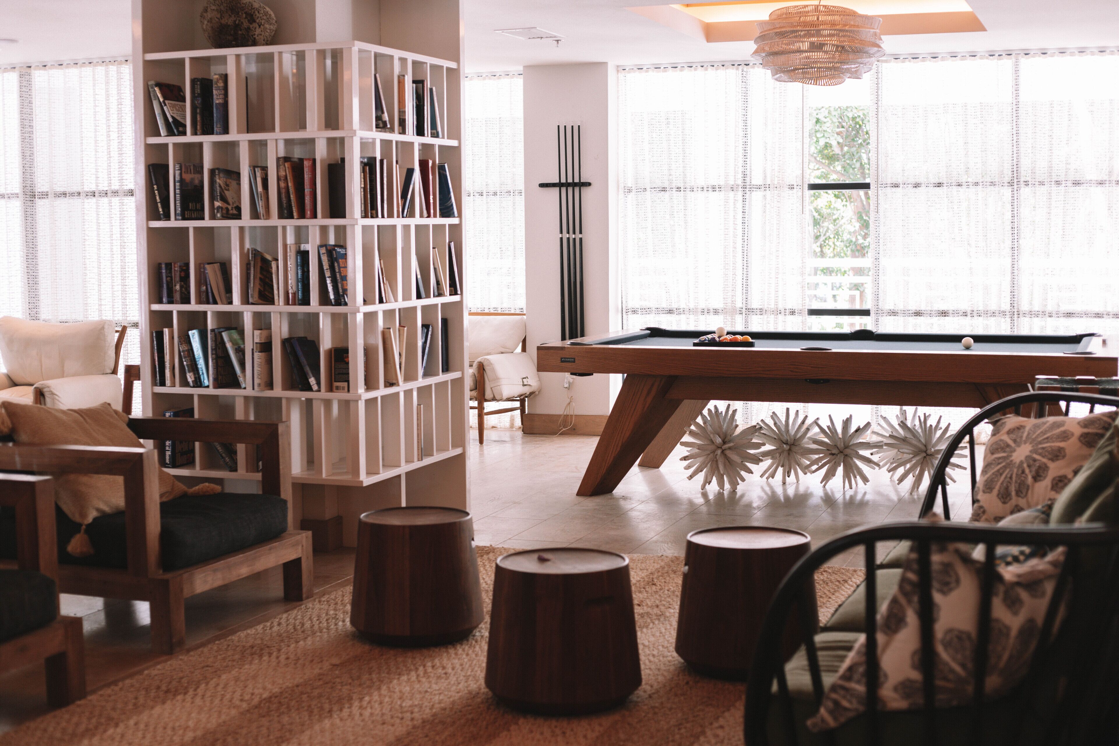 A cozy living room with a pool table, a large bookshelf, and comfortable seating.