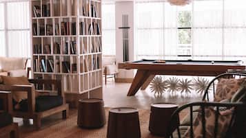 A cozy living room with a pool table, a large bookshelf, and comfortable seating.