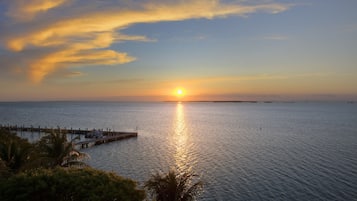 A sunset over a calm sea with a pier extending into the water.