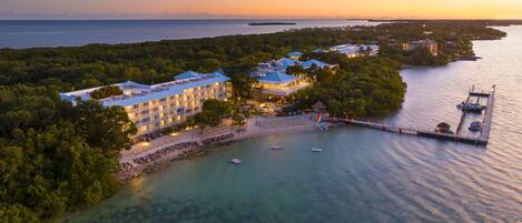 A resort with multiple buildings, a dock, and clear waters.