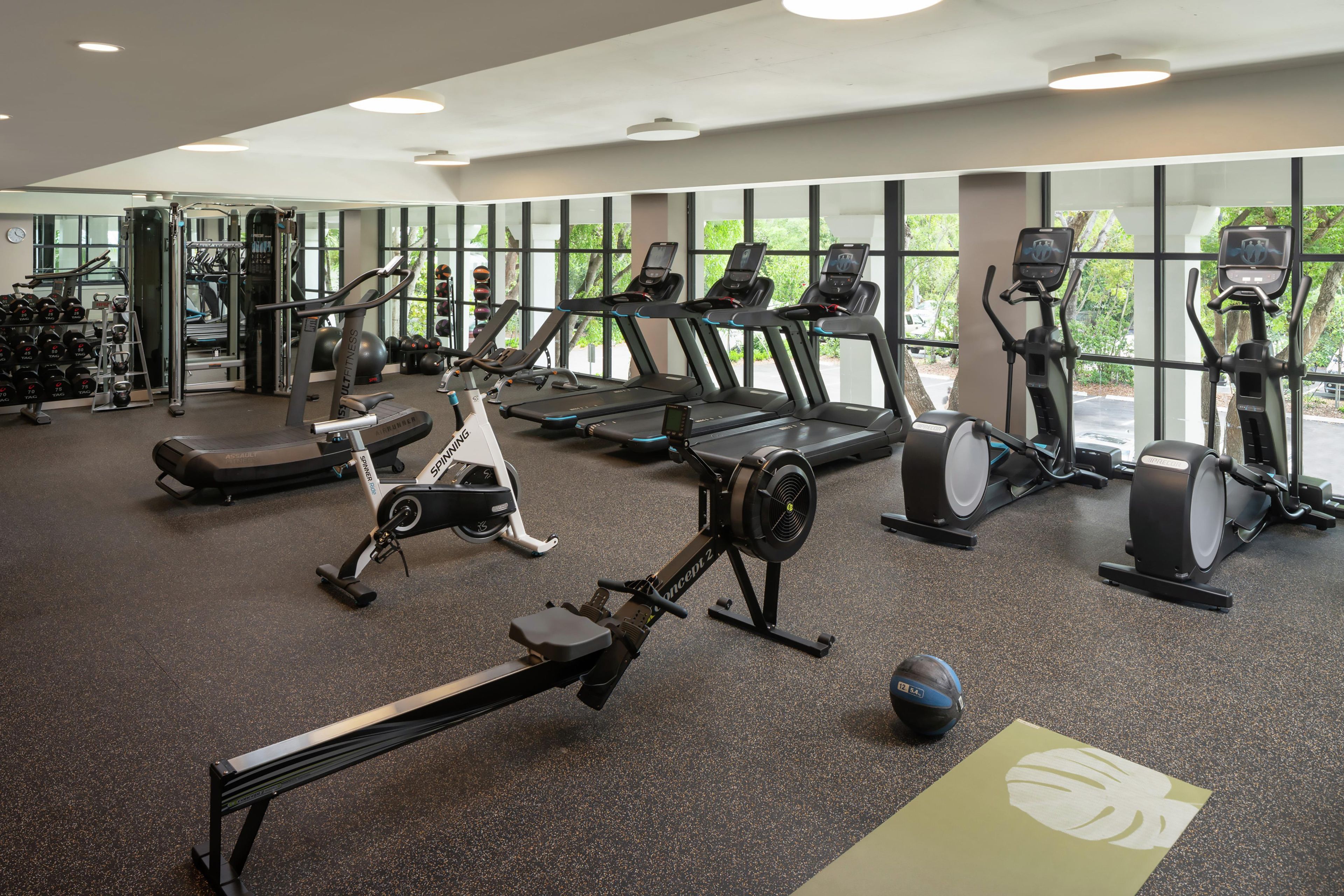 Ein Fitnessstudio mit unterschiedlichen Trainingsgeräten, darunter Laufbänder, Ergometer und Kraftgeräte.