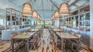 A spacious dining area with high ceilings, wicker furniture, and large windows. - Baker's Cay Resort Key Largo, Curio Collection by Hilton (Key Largo)