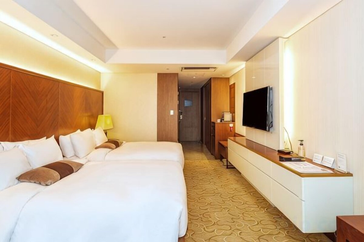 Une chambre d’hôtel avec deux lits, un bureau, une télévision et un espace réception.