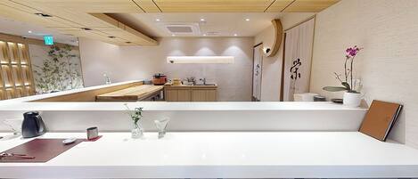 Un hall d’hôtel moderne comprenant un comptoir d’accueil, un espace salon et une petite kitchenette.
