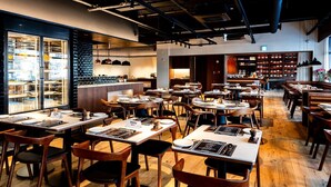 A restaurant with multiple tables and chairs, a bar area, and a display case with items. - Koreana Hotel (Seoul)