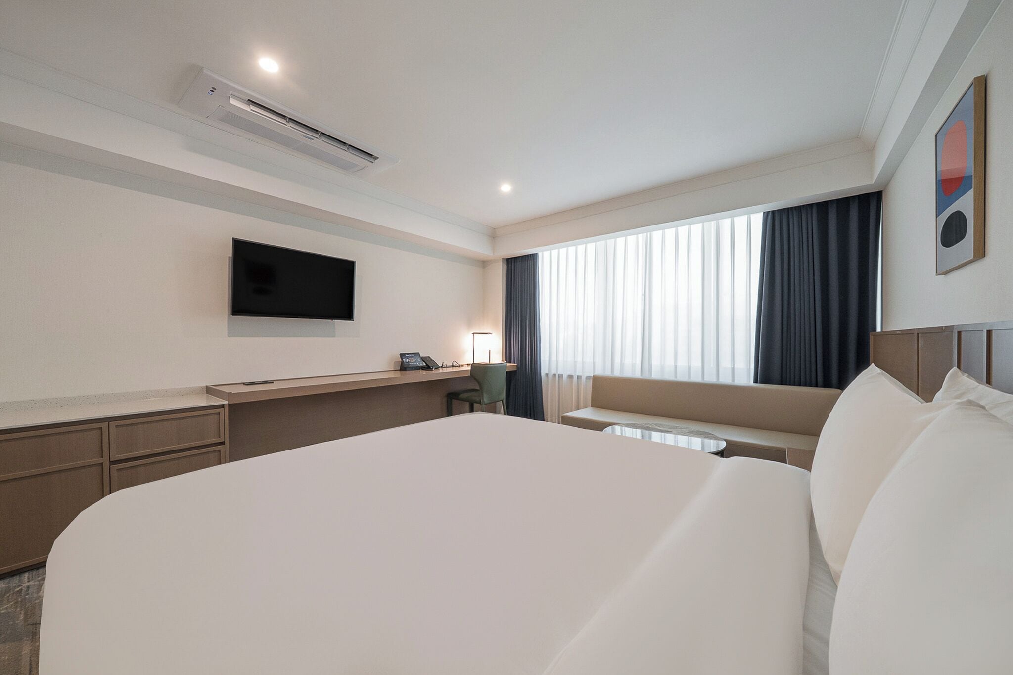 Une chambre d’hôtel avec un grand lit, un bureau, un téléviseur à écran plat et une fenêtre avec des rideaux.