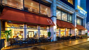 A modern building with a restaurant on the ground floor, featuring large awnings and outdoor seating. - Koreana Hotel (Seoul)