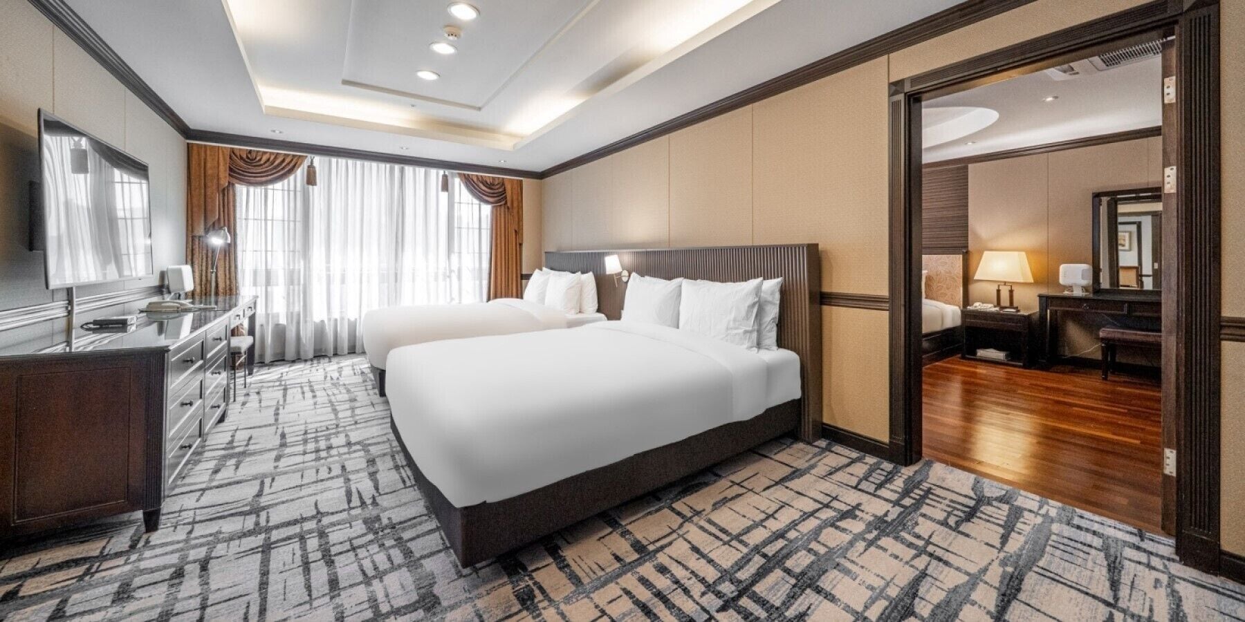 Habitación de hotel con una cama grande, un escritorio, un espejo y vista al pasillo.