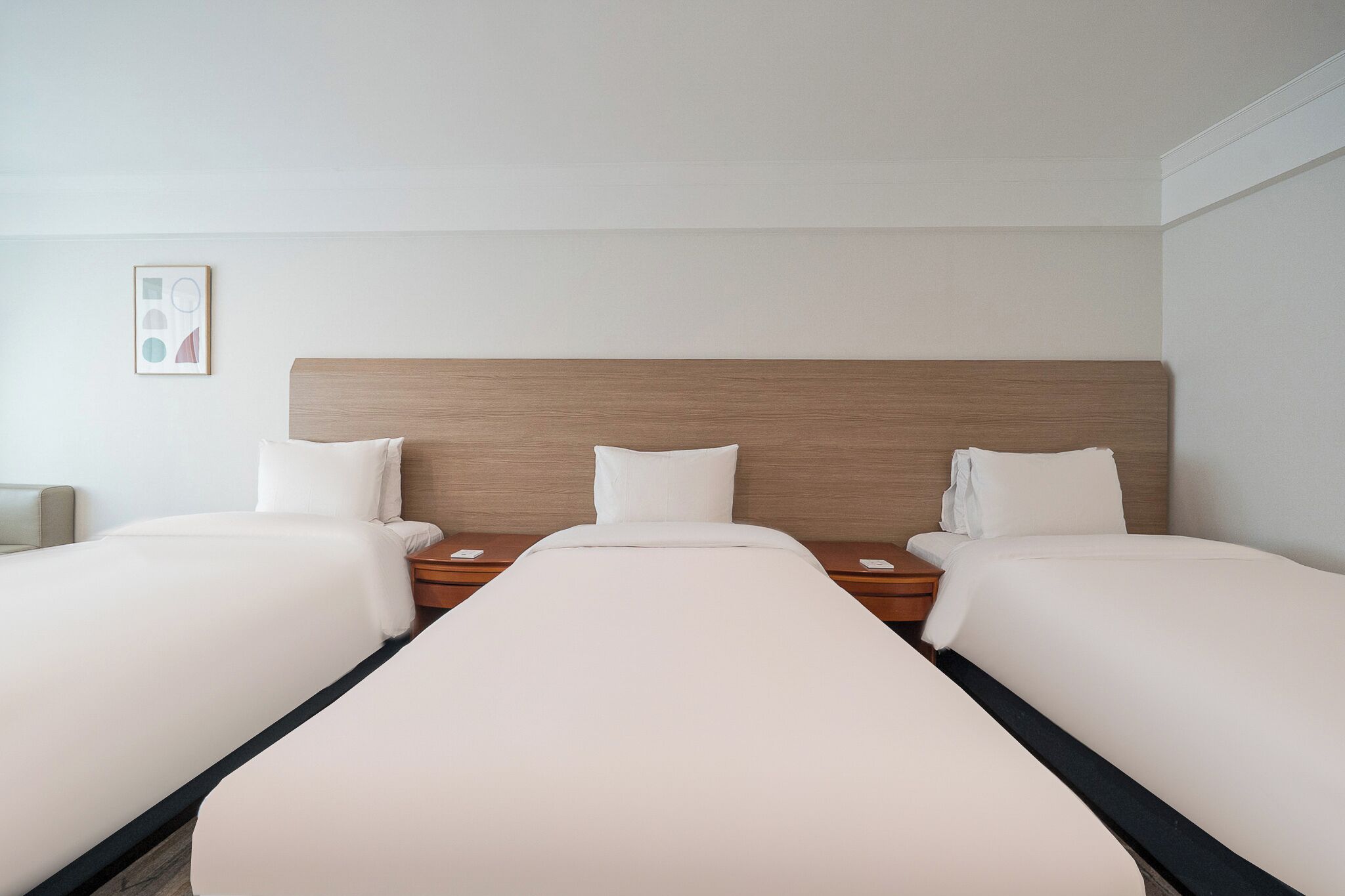 Una habitación de hotel con una cama grande, dos mesitas de noche y un cabecero.