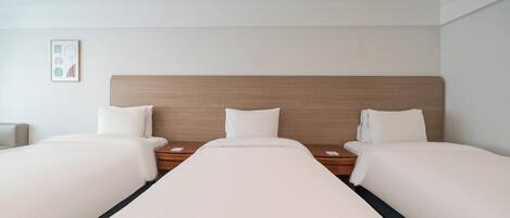 Una habitación de hotel con una cama grande, dos mesitas de noche y un cabecero.