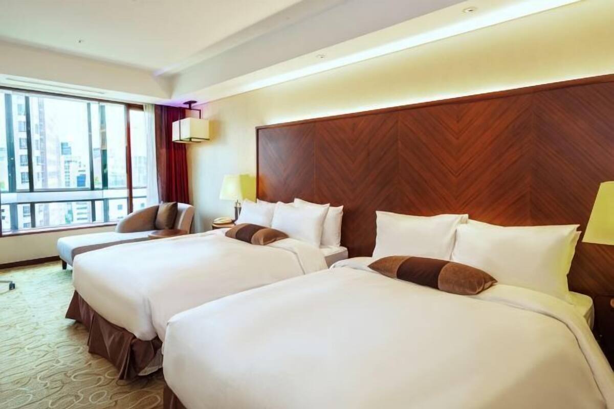 Ein Hotelzimmer mit zwei großen Betten, Blick auf die Stadt und moderner Einrichtung.