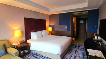 Habitación de hotel con una cama grande, lámparas de noche, un escritorio con teléfono y una silla.