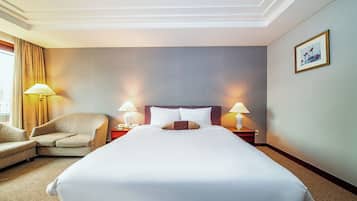A hotel room with a large bed, two bedside lamps, a chair, and a nightstand.