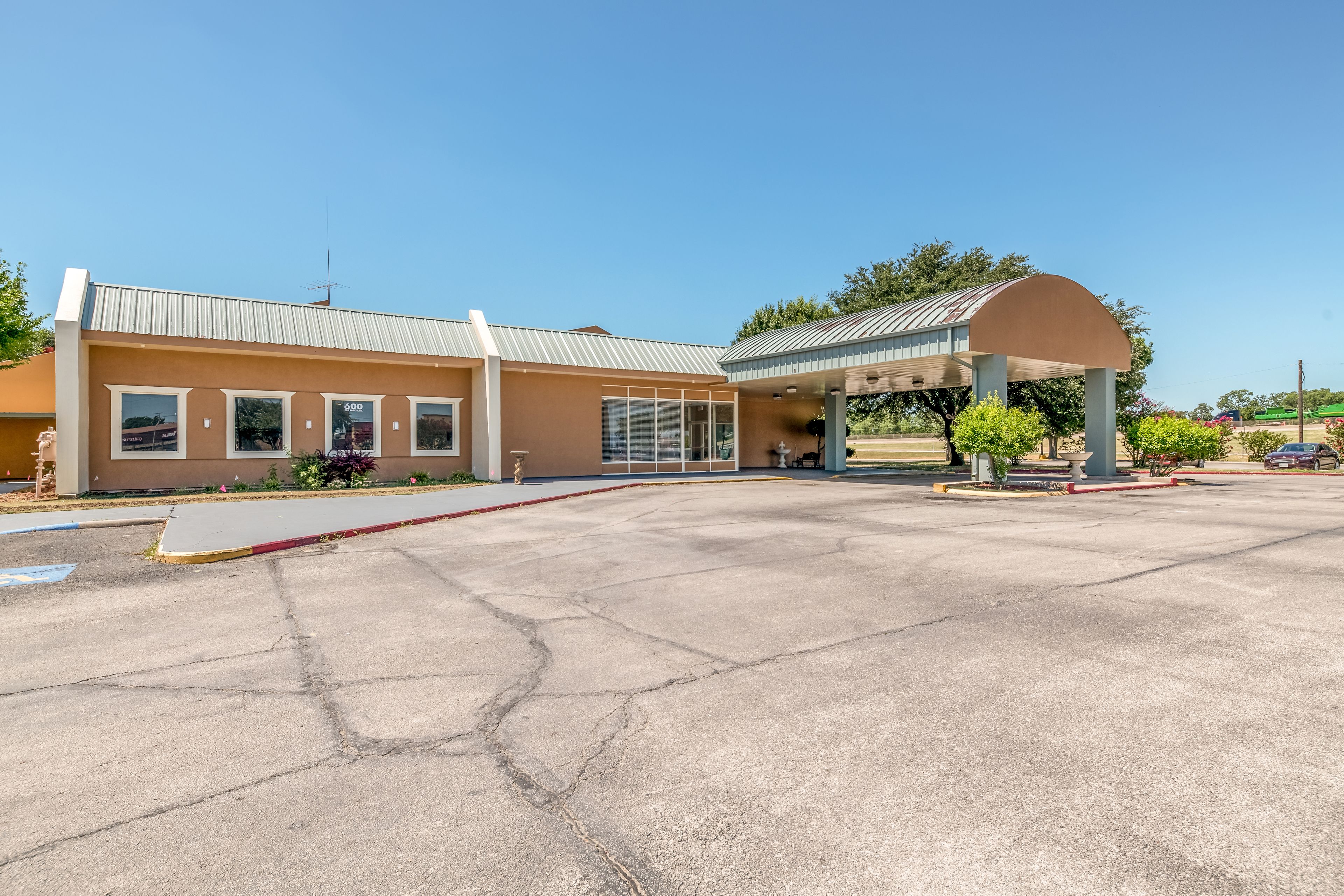 A building with a covered entrance and a parking lot.