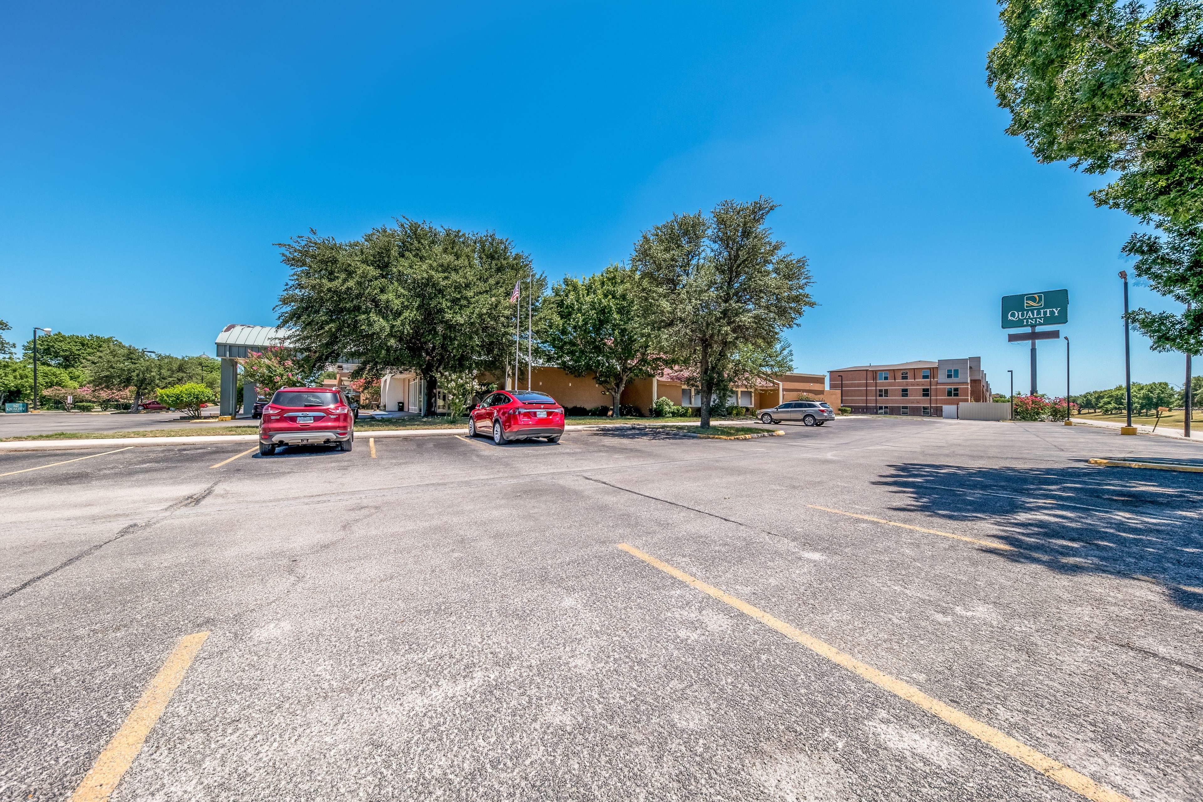 A parking lot with cars, a building labeled "Quality Inn," and trees.