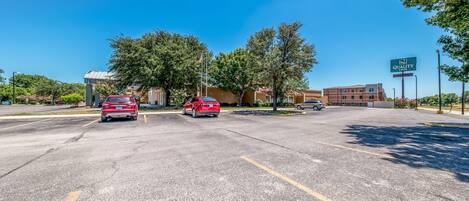 A parking lot with cars, a building labeled "Quality Inn," and trees.