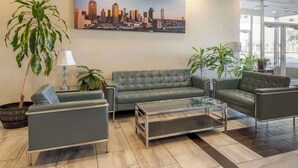 A modern lobby with a green leather sofa, a glass coffee table, and potted plants.