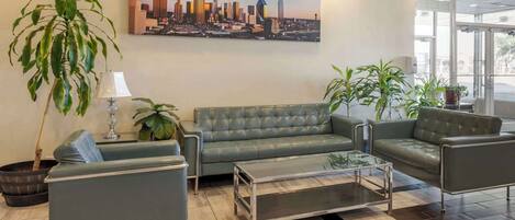 Un lobby moderno con un sofá de cuero verde, una mesa de centro de vidrio y plantas en macetas.