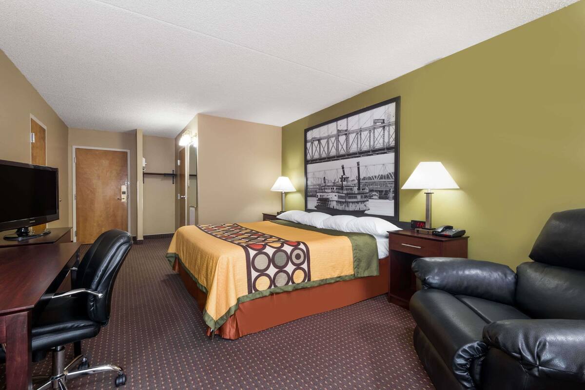 Ein Hotelzimmer mit einem Bett, einem Schreibtisch mit Fernseher, einer Ledersofa und zwei Lampen.