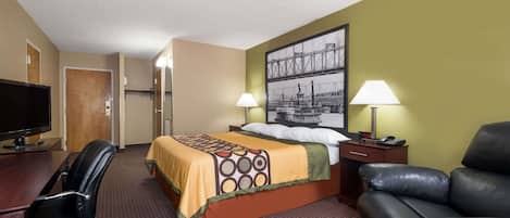 A hotel room with a bed, a desk with a TV, a leather couch, and two lamps.