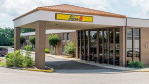 Un hotel Super 8 con entrada techada, fachada de ladrillo y ventanas amplias.