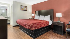 Una habitación de hotel con cama, mesitas de noche, una silla y un escritorio.