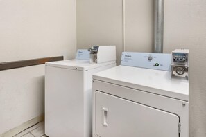 A laundry area with two white washing machines, a control panel, and a payment terminal.