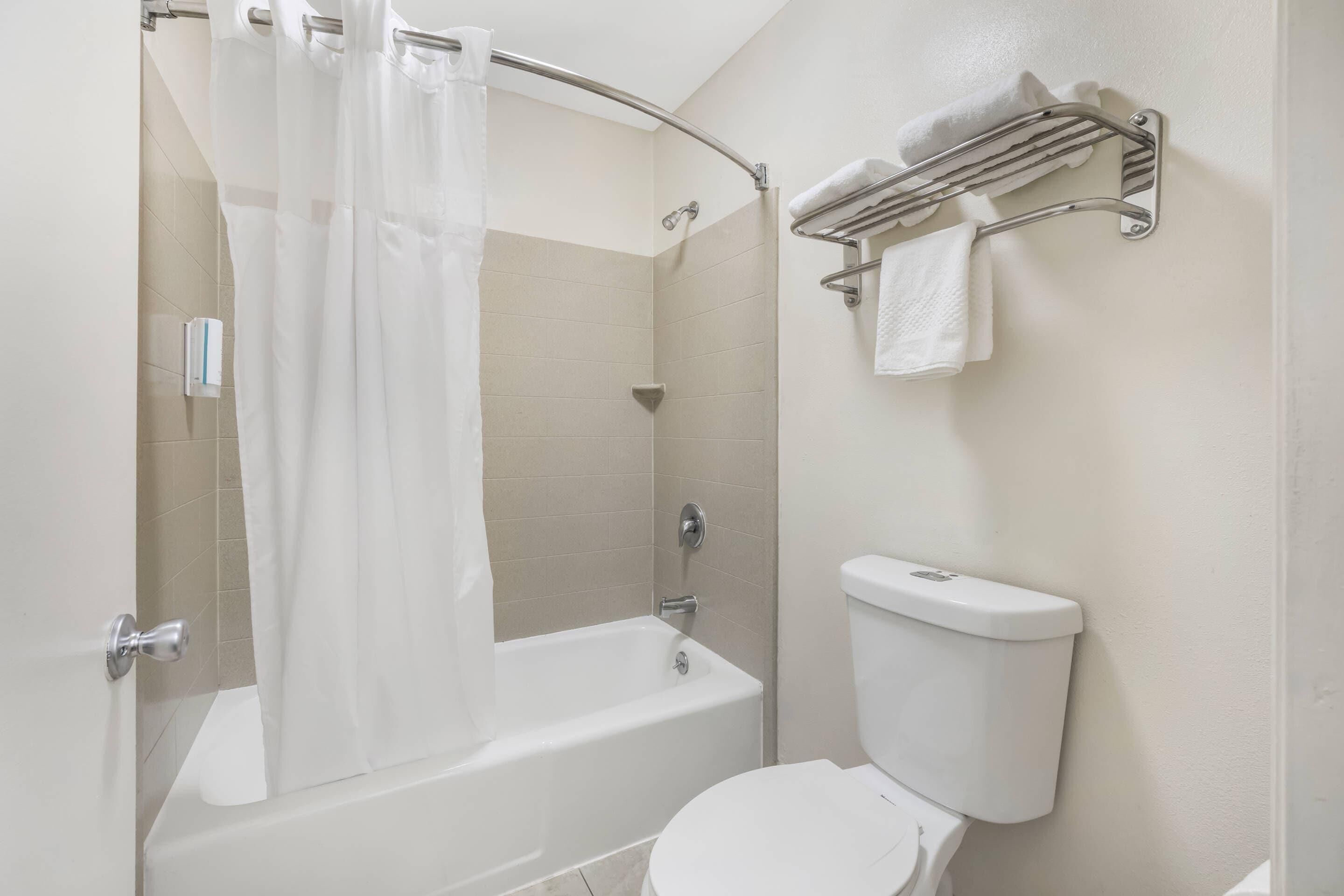 A bathroom with a bathtub, toilet, shower curtain, and towel rack.