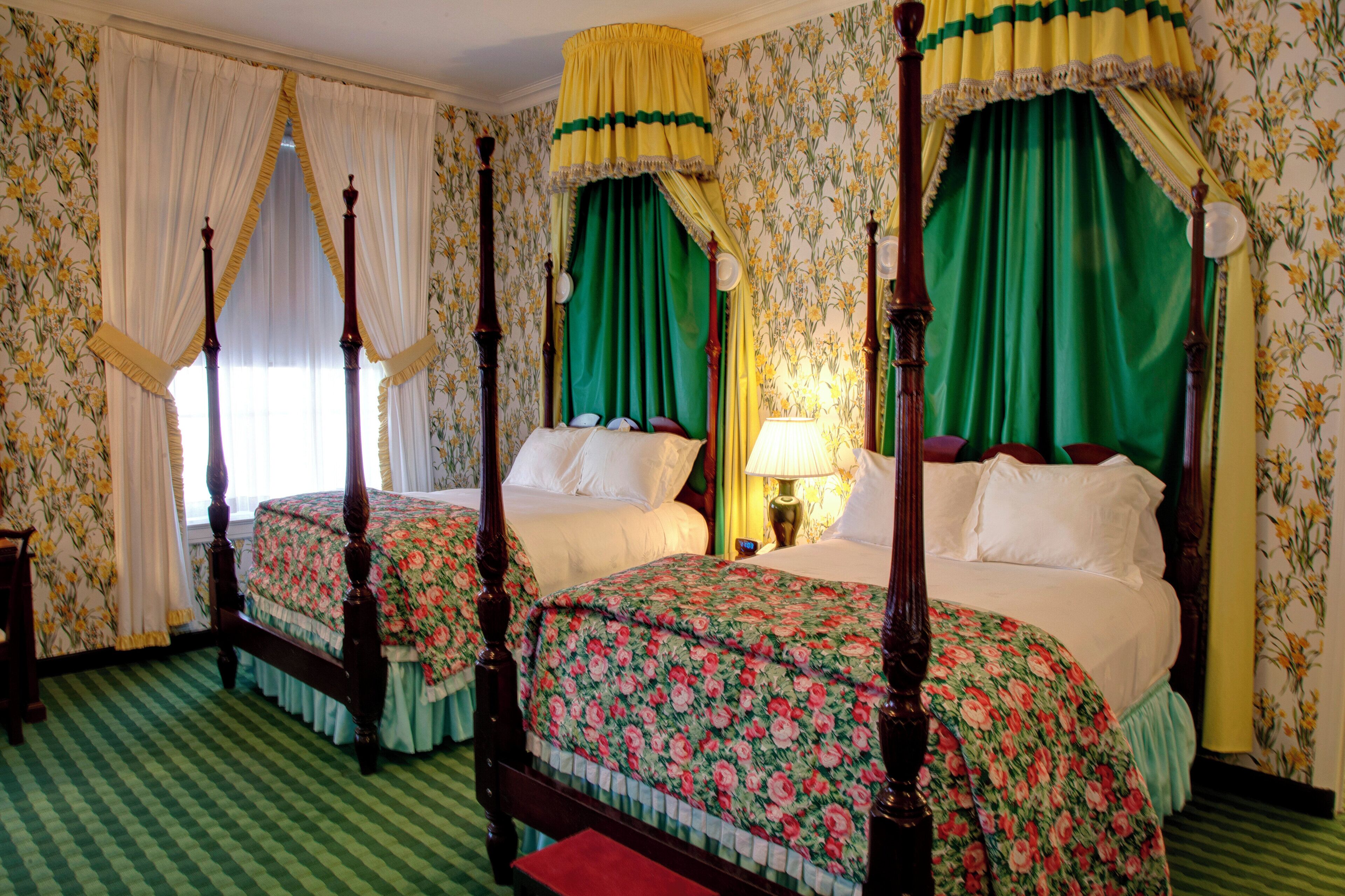 A four-poster bed with floral bedspreads, a canopy, and a checkered floor.