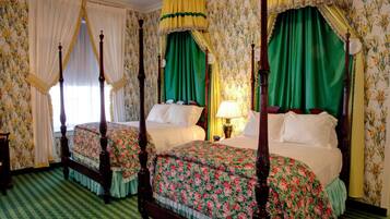 A four-poster bed with floral bedspreads, a canopy, and a checkered floor.