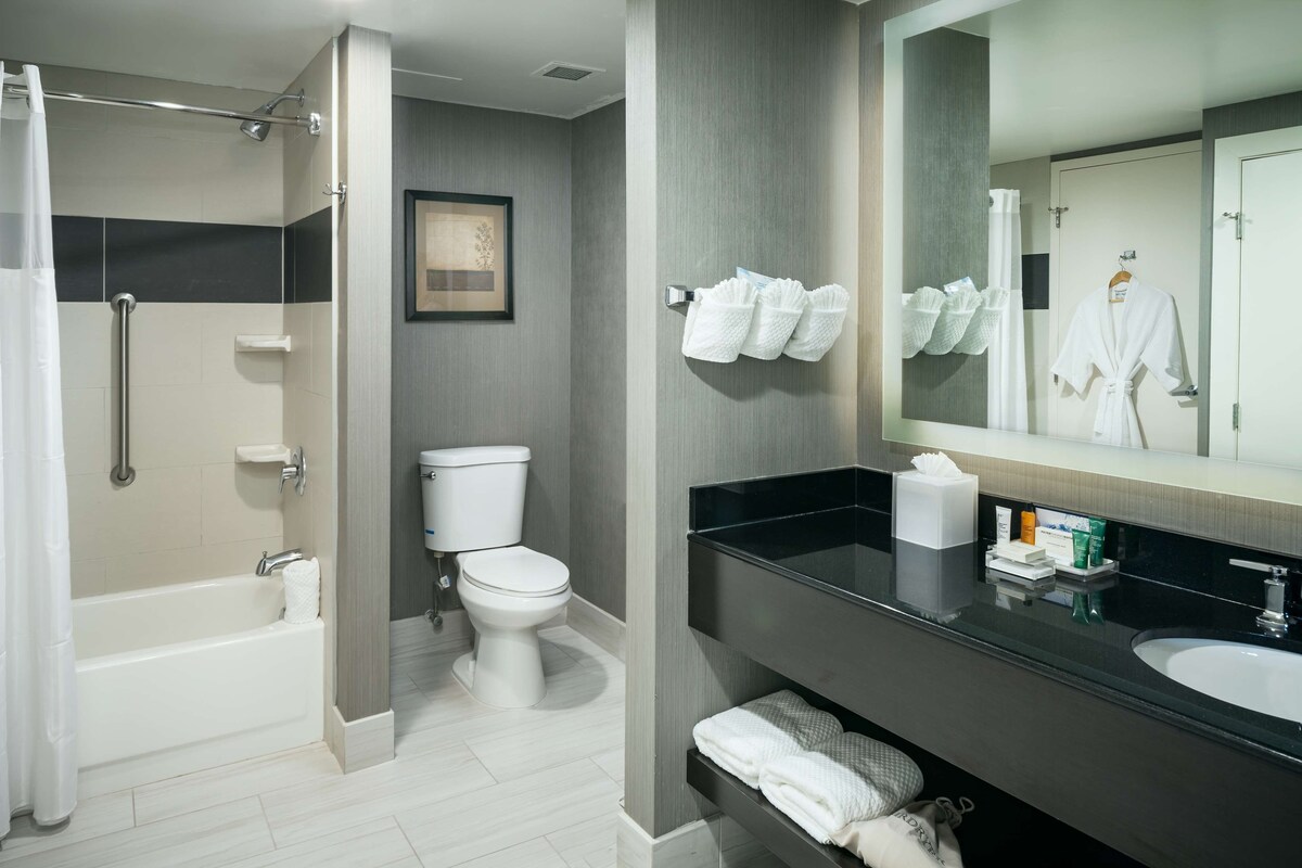 A modern bathroom with a bathtub, toilet, and vanity with a large mirror.