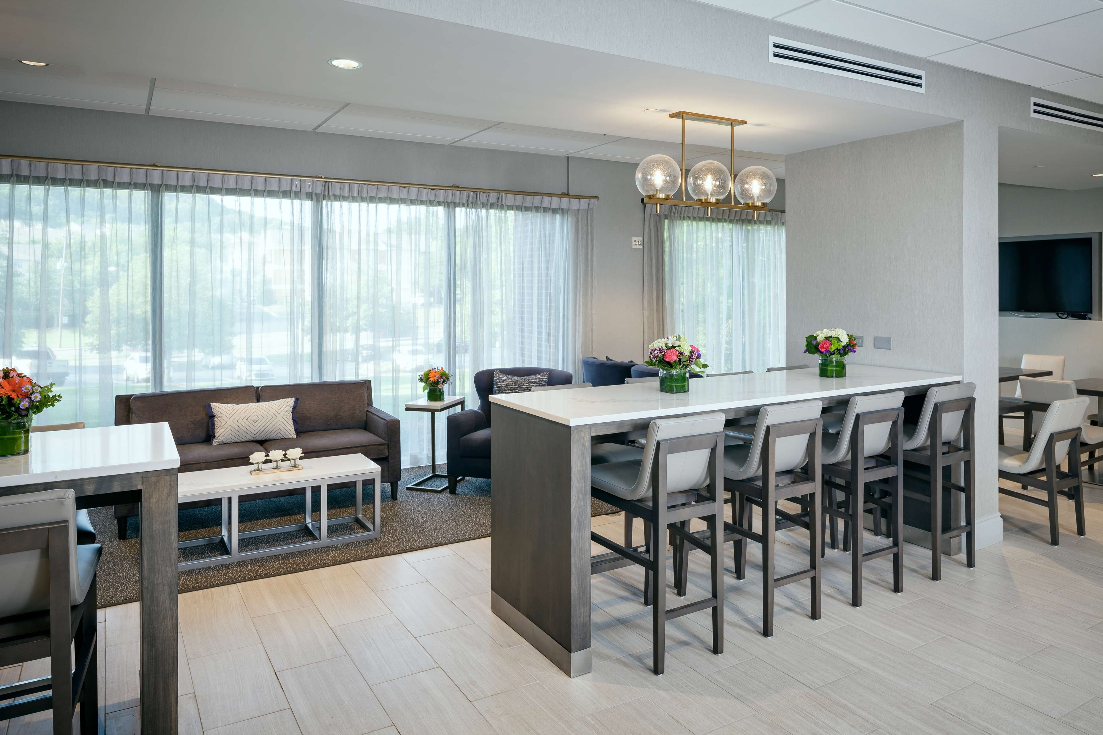 Uma sala de estar moderna com sofá, mesa de centro e área de jantar com bar.