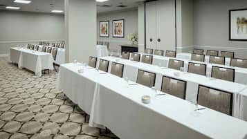 A conference room with long tables, chairs, and a patterned carpet.