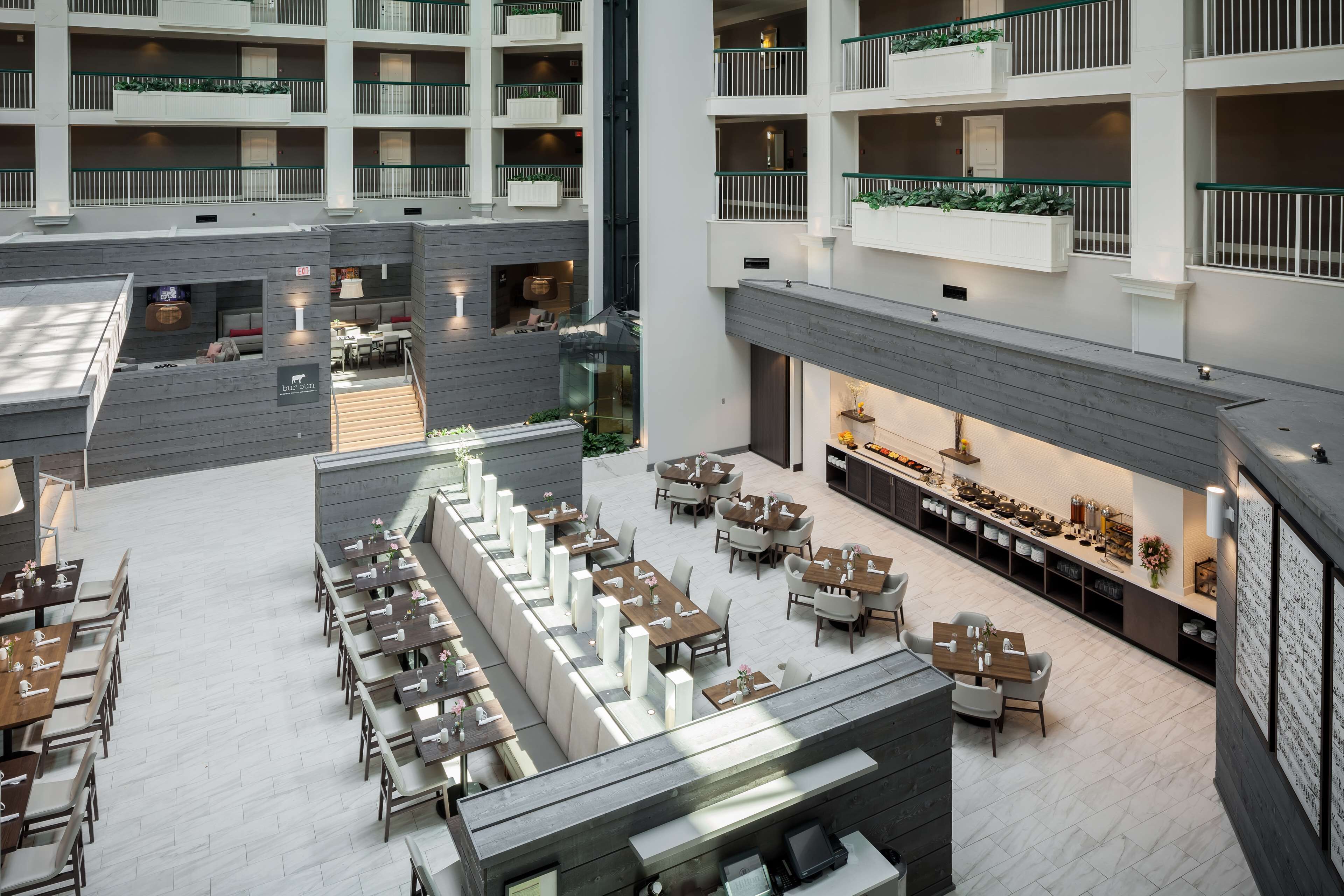 A multi-level hotel atrium with a central open space, dining area, and a restaurant.