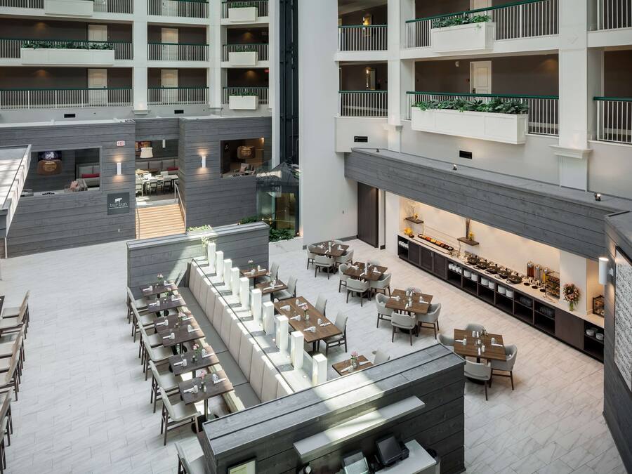 A multi-level hotel atrium with a central open space, dining area, and a restaurant.