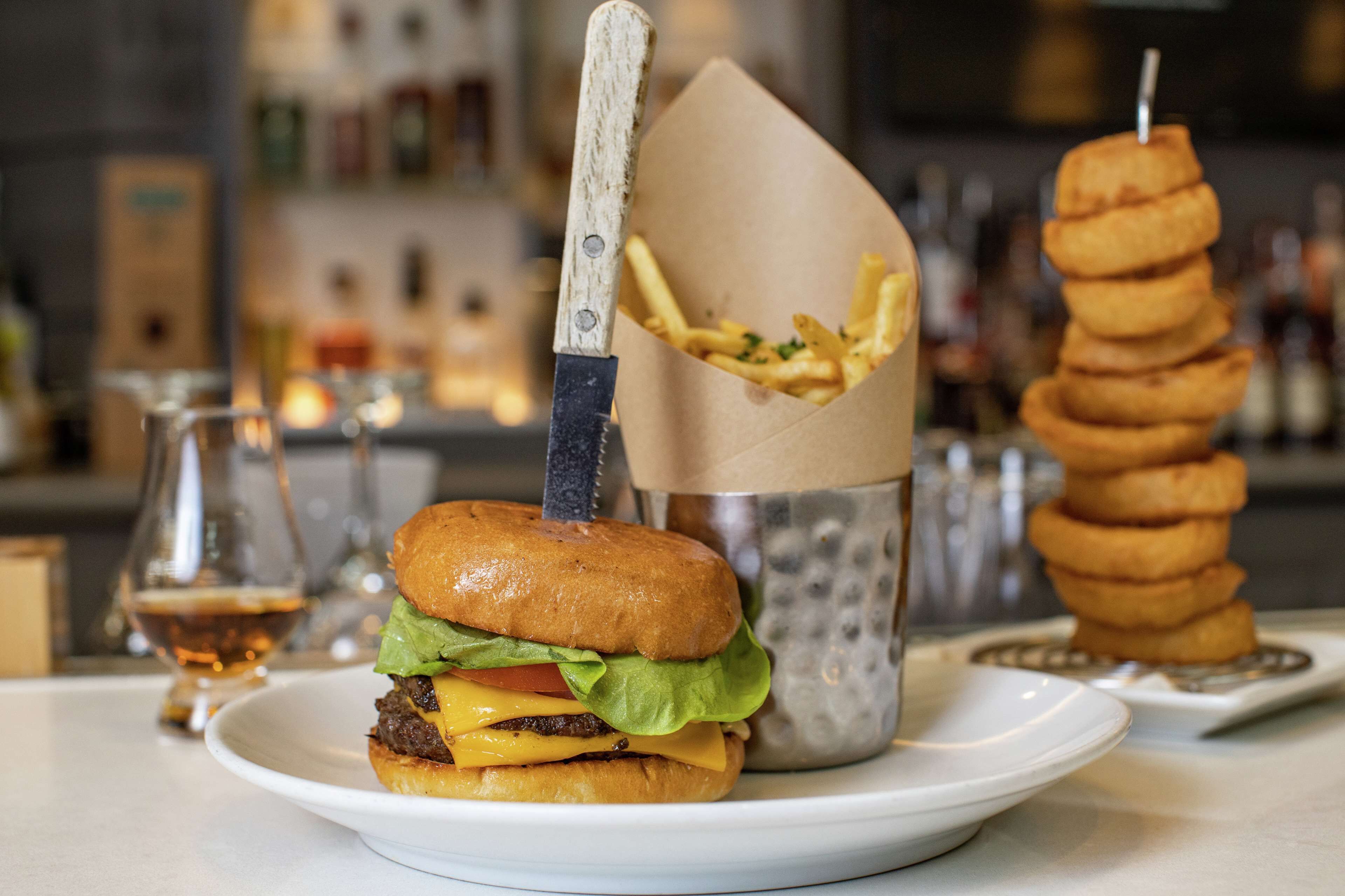 A burger with fries and a drink on a plate.