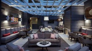 Un espacio lounge moderno con un sofá central, asientos alrededor y una mesa de comedor.
