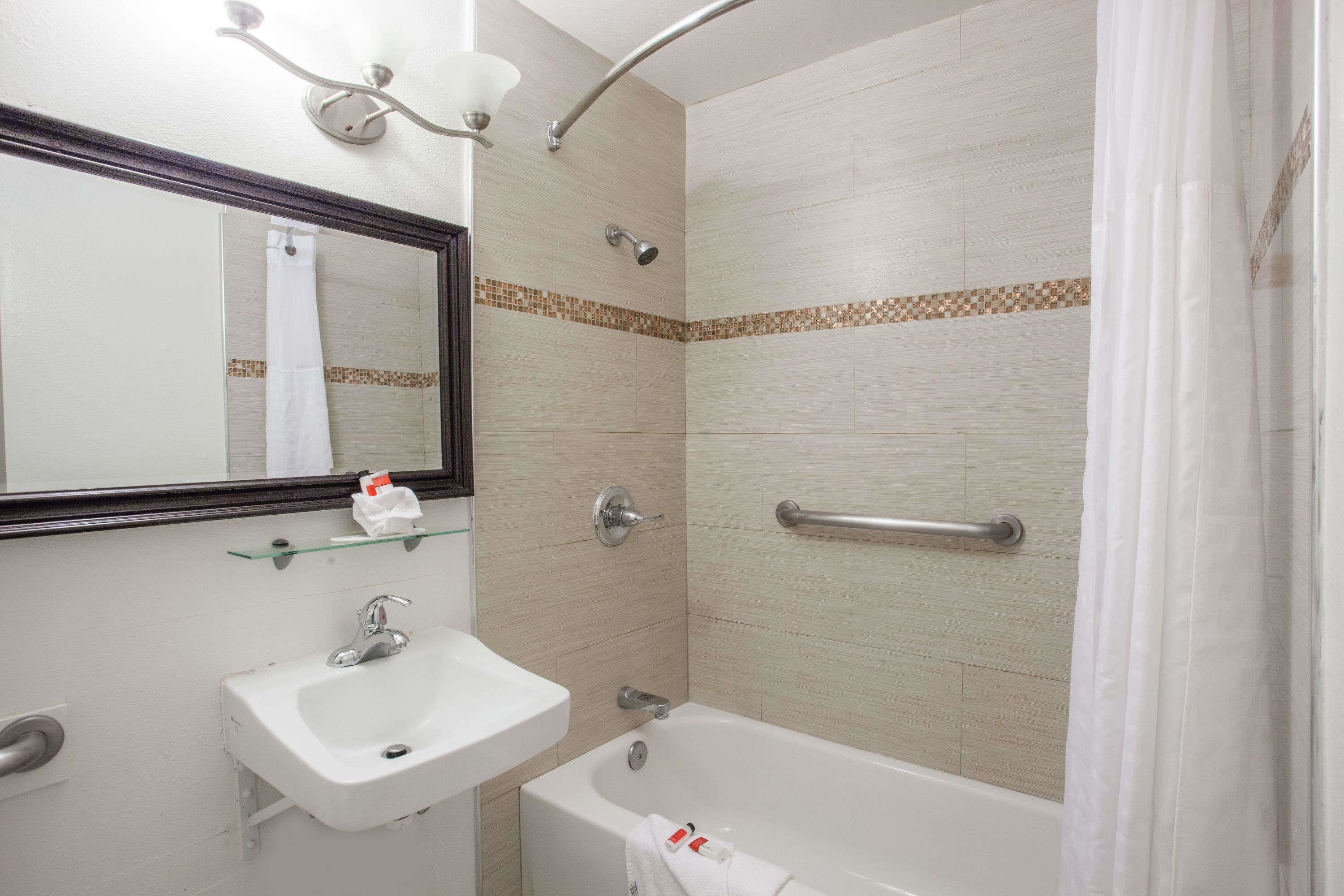 A bathroom with a sink, mirror, shower, and bathtub.