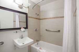 Baño con lavamanos, espejo, ducha y bañera.