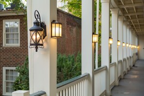 A covered outdoor corridor with white columns and a brick wall in the background. - Linden Row Inn (Richmond)