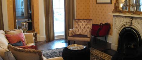 A traditional living room with a sofa, armchair, ottoman, and fireplace.